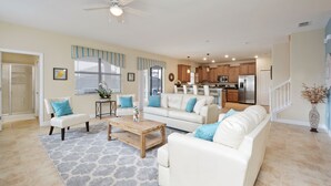 Ein geräumiges Wohnzimmer mit einem weißen Sofa, einem Couchtisch und einem Deckenventilator.