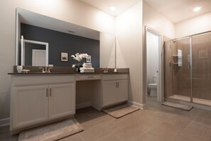 A modern bathroom with a dark accent wall, a large mirror, a shower enclosure, and a vanity with a towel rack. - 630sst- The Retreat At Championsgate 5 Bedroom Home by RedAwning (Davenport)