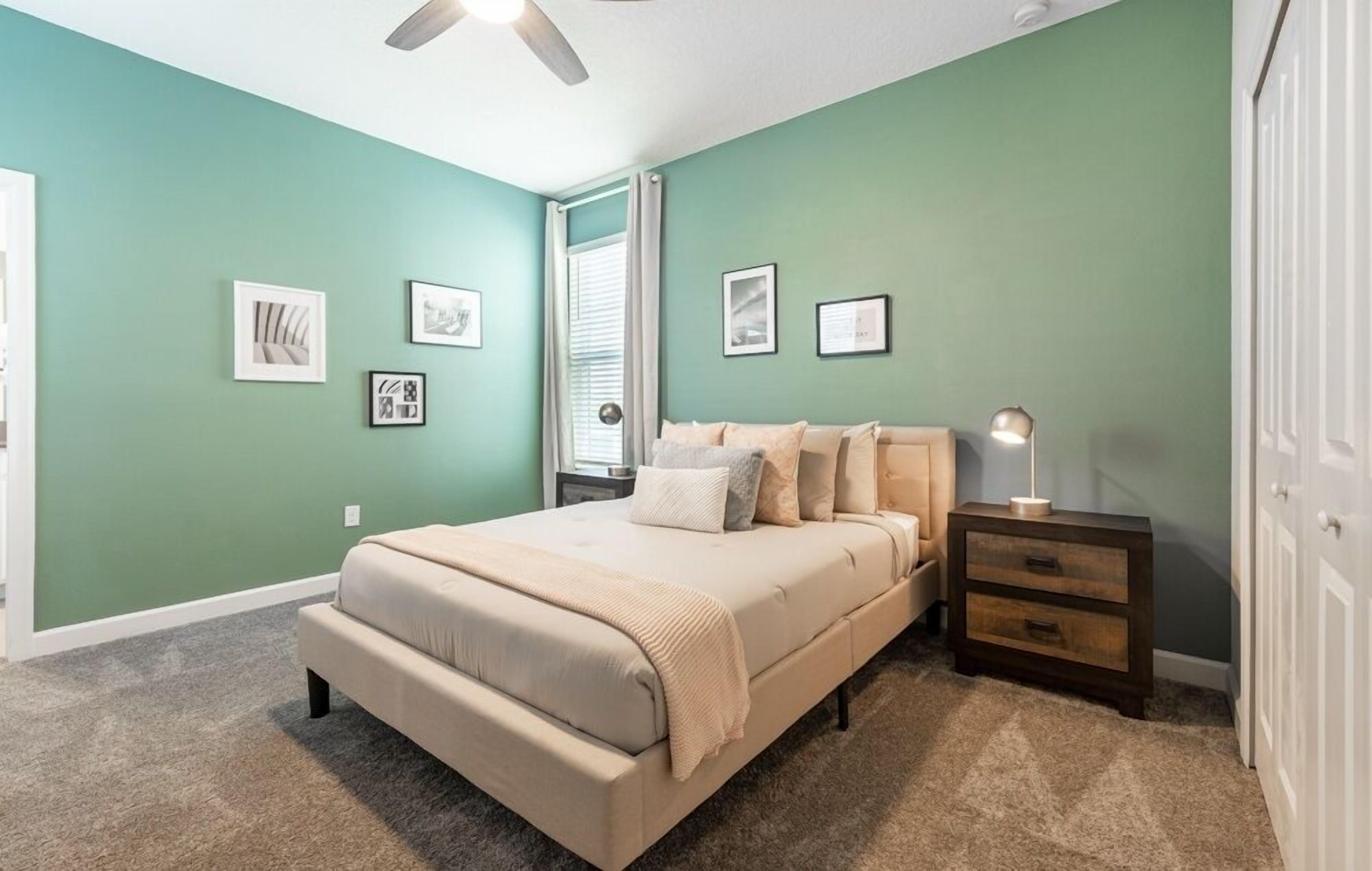 A bedroom with a bed, nightstand, and wall art.
