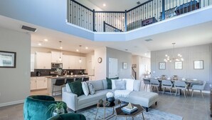 A spacious living area with a modern sofa, a dining table, and a kitchen in the background.
