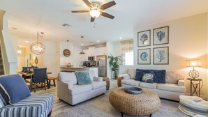A spacious living room with a ceiling fan, a dining area, and a kitchen in the background. - 1589mvd-the Retreat At Championsgate 4 Bedroom Townhouse by RedAwning (Davenport)