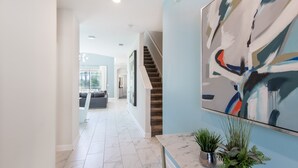 A modern interior with a marble floor, a staircase, and a large abstract painting on the wall.
