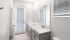 A modern bathroom with a double sink vanity, a large mirror, and a toilet. - 601dsd-the Retreat At Championsgate 5 Bedroom Home by RedAwning (Kissimmee)