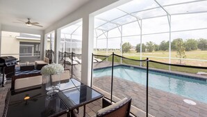 A poolside area with a glass table, wicker chairs, and a view of a swimming pool. - 9028sh-the Retreat At Championsgate 6 Bedroom Home by RedAwning (Davenport)