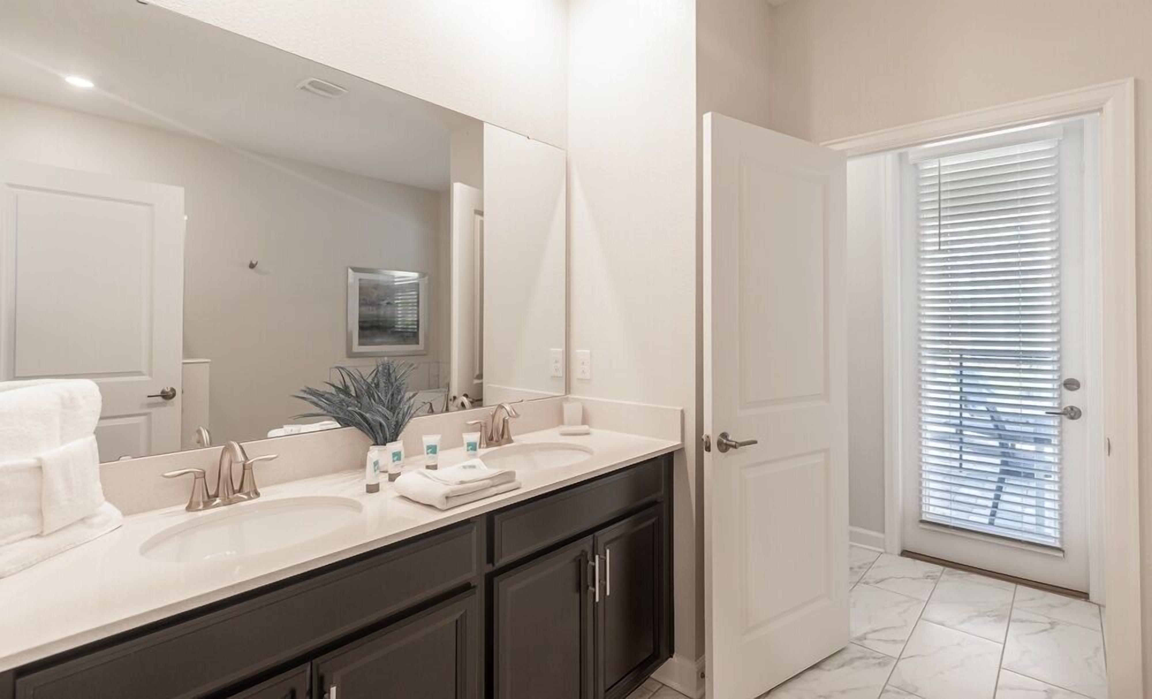 A modern bathroom with two sinks, dark cabinets, and a large mirror.