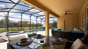 A covered patio with a pool, outdoor furniture, and a view of the neighborhood. - 7547oml-solterra Resort 6 Bedroom Home by RedAwning (Davenport)