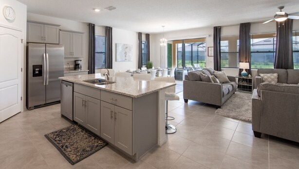 A modern kitchen with a central island, stainless steel appliances, and a dining area with a sofa and table. - 7547oml-solterra Resort 6 Bedroom Home by RedAwning (Davenport)