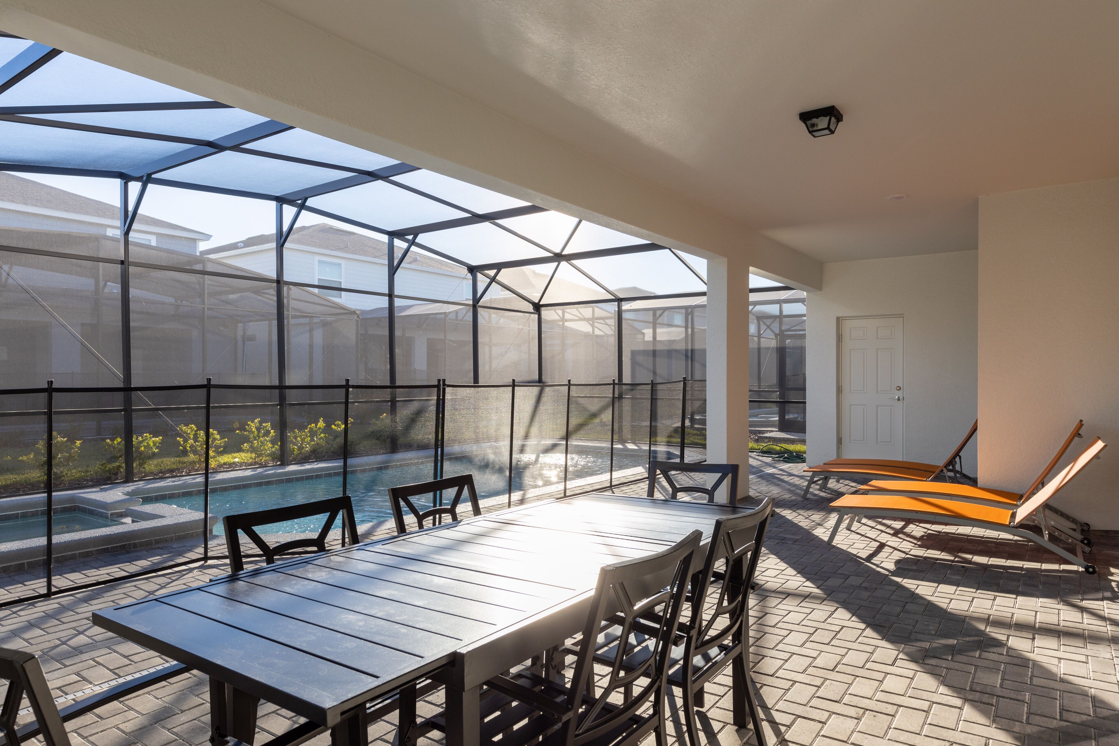 Un espace extérieur abrité comprenant une piscine, une table avec des chaises et des fauteuils de relaxation.