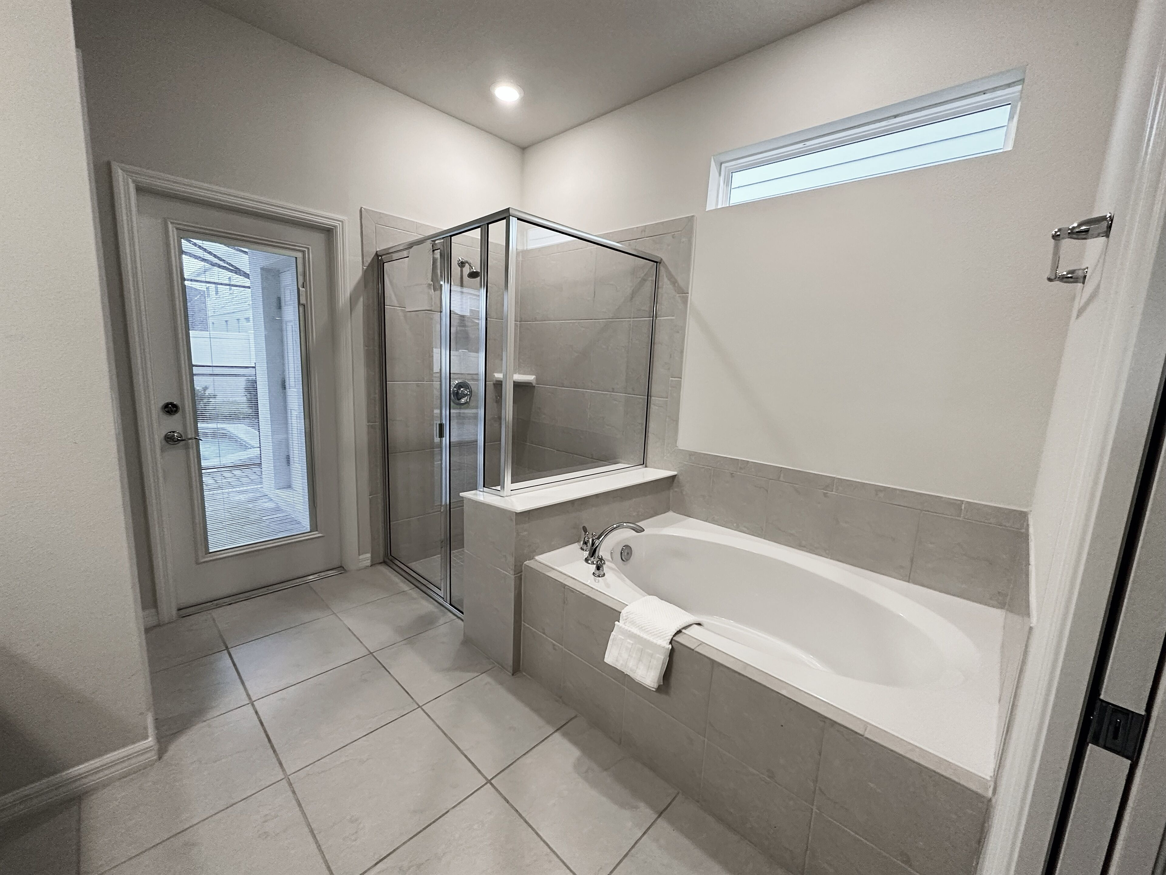 Un baño moderno con ducha acristalada, bañera independiente y una pequeña ventana sobre el lavabo.