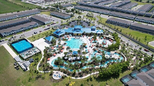 An aerial view of a resort with multiple buildings, a central pool area, and a smaller pool. - 2127lc- Windsor Island 10 Bedroom Home by RedAwning (Davenport)
