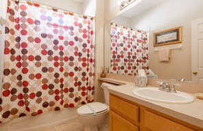 Une salle de bain équipée de toilettes, d’un lavabo et d’un rideau de douche à motifs à pois.