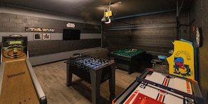 A room with a foosball table, pool table, and Star Wars themed decor.