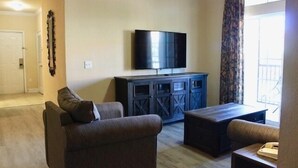 Una sala de estar con un televisor de pantalla plana montado en la pared, un mueble de madera oscura para el equipo de sonido y dos sofás.