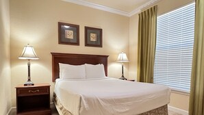 A neatly made bed with a headboard, two bedside tables with lamps, and two framed pictures on the wall. - 1301tt Unit 9108- Tuscana Resort 3 Bedroom Condo by RedAwning (Davenport)