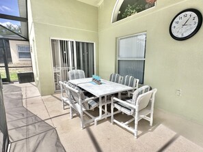 A patio with a table and chairs, a clock on the wall, and a window with blinds. - 777bd - West Haven Gated Community 4 Bedroom Home by RedAwning (Davenport)