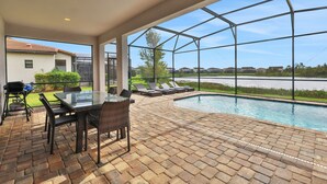 Un patio couvert avec une structure en verre, une piscine et du mobilier d’extérieur.