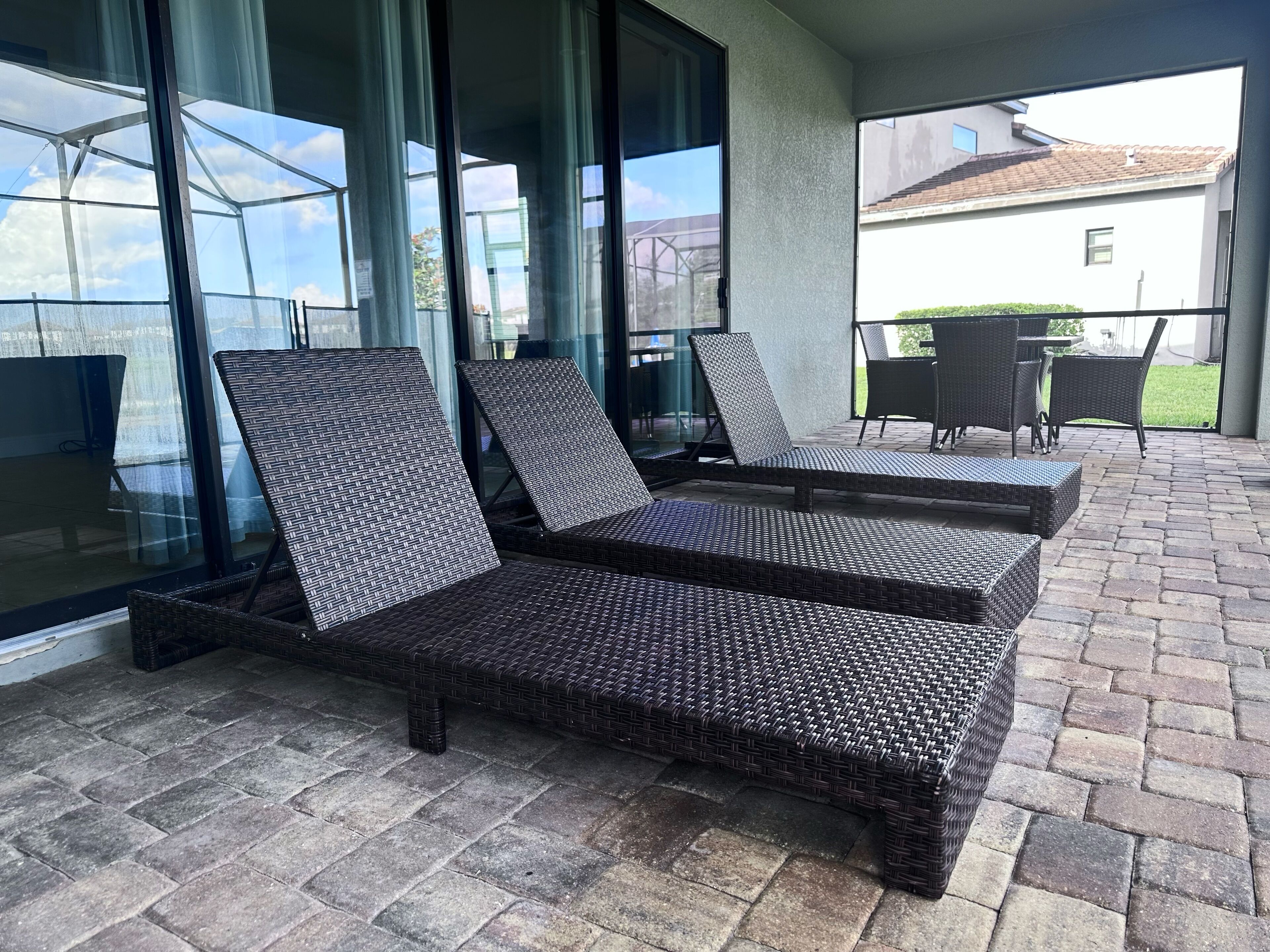 A covered outdoor seating area with wicker lounge chairs and a table.