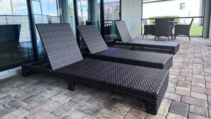 Ein überdachter Außenbereich mit Korlounge-Stühlen und einem Tisch.
