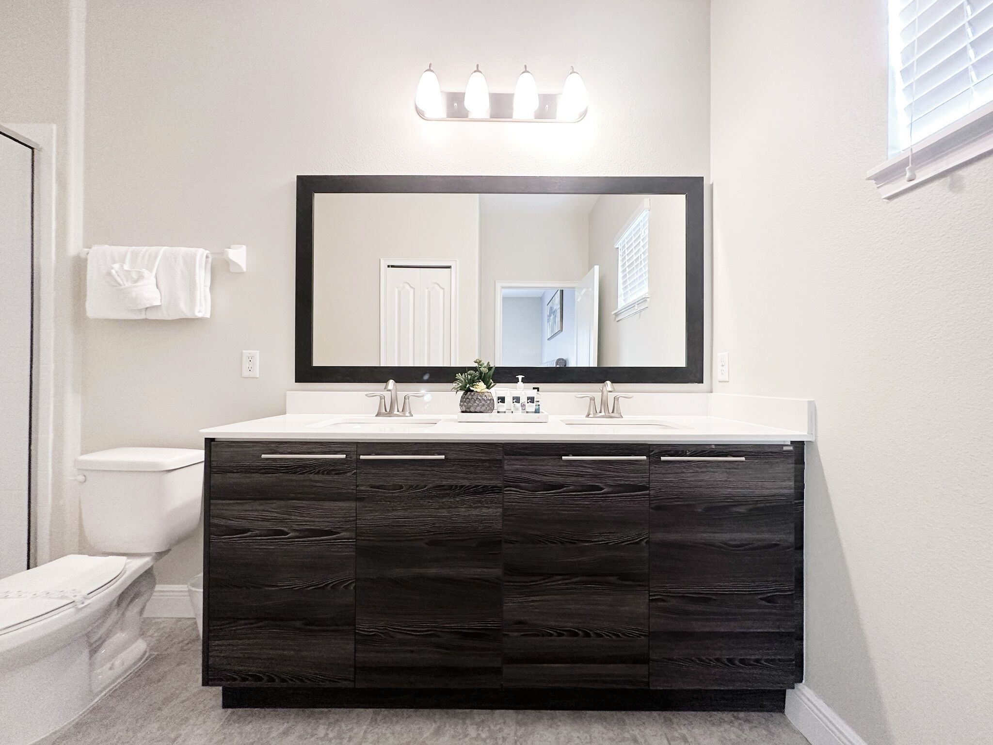 A bathroom with a dark wood vanity, white sink, and a large mirror above the vanity.