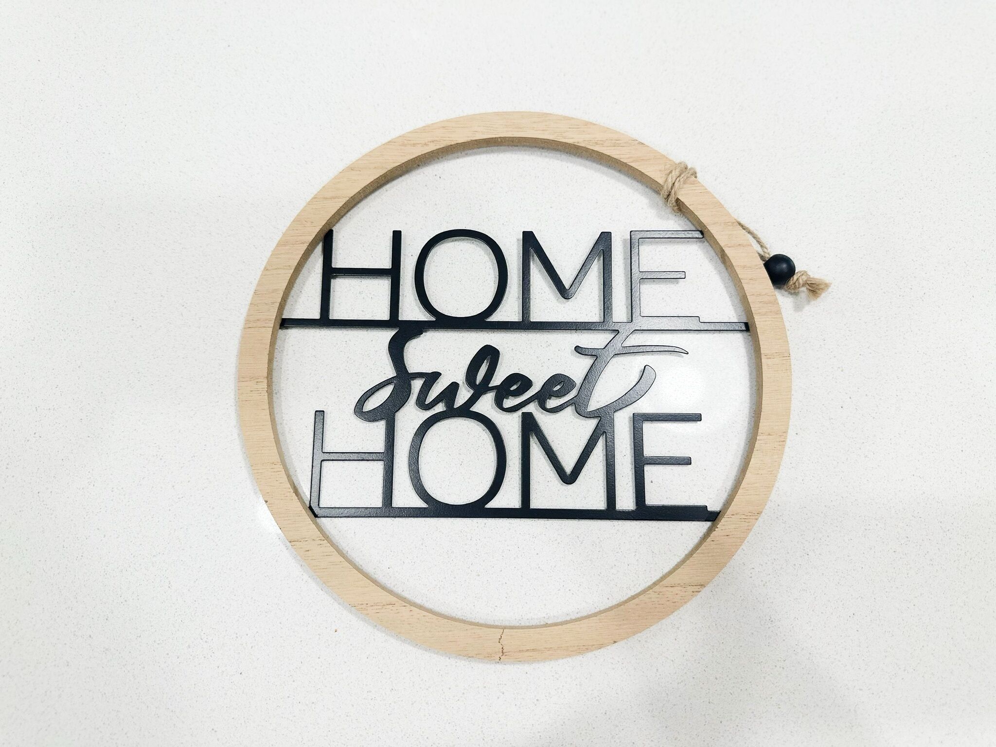 Un letrero de madera circular con la inscripción 'HOME SWEET HOME' en una tipografía decorativa.