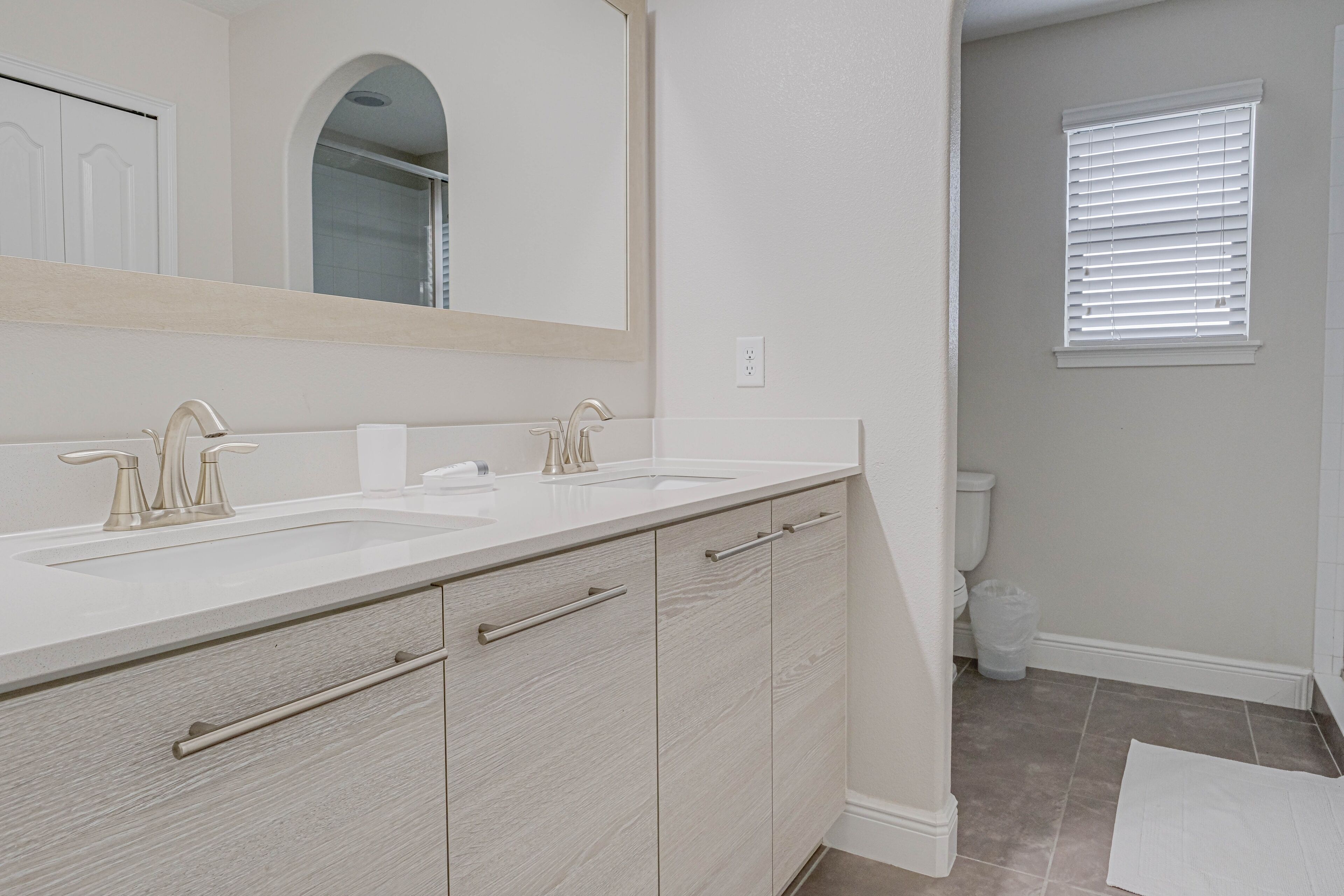 A bathroom with two sinks, a mirror, and a toilet.