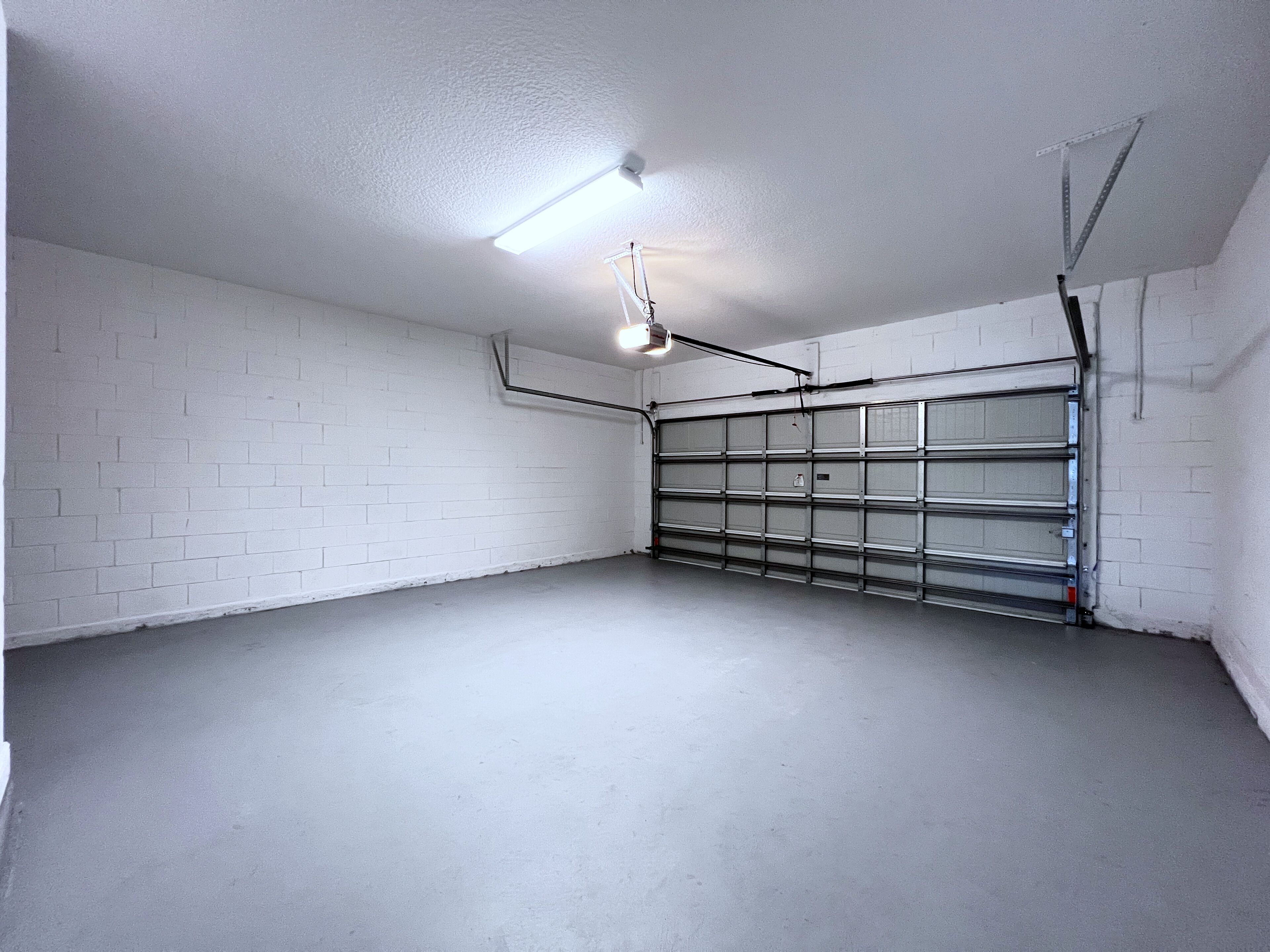 Een garage met witte bakstenen muren, een betonnen vloer en een metalen garagepoort.