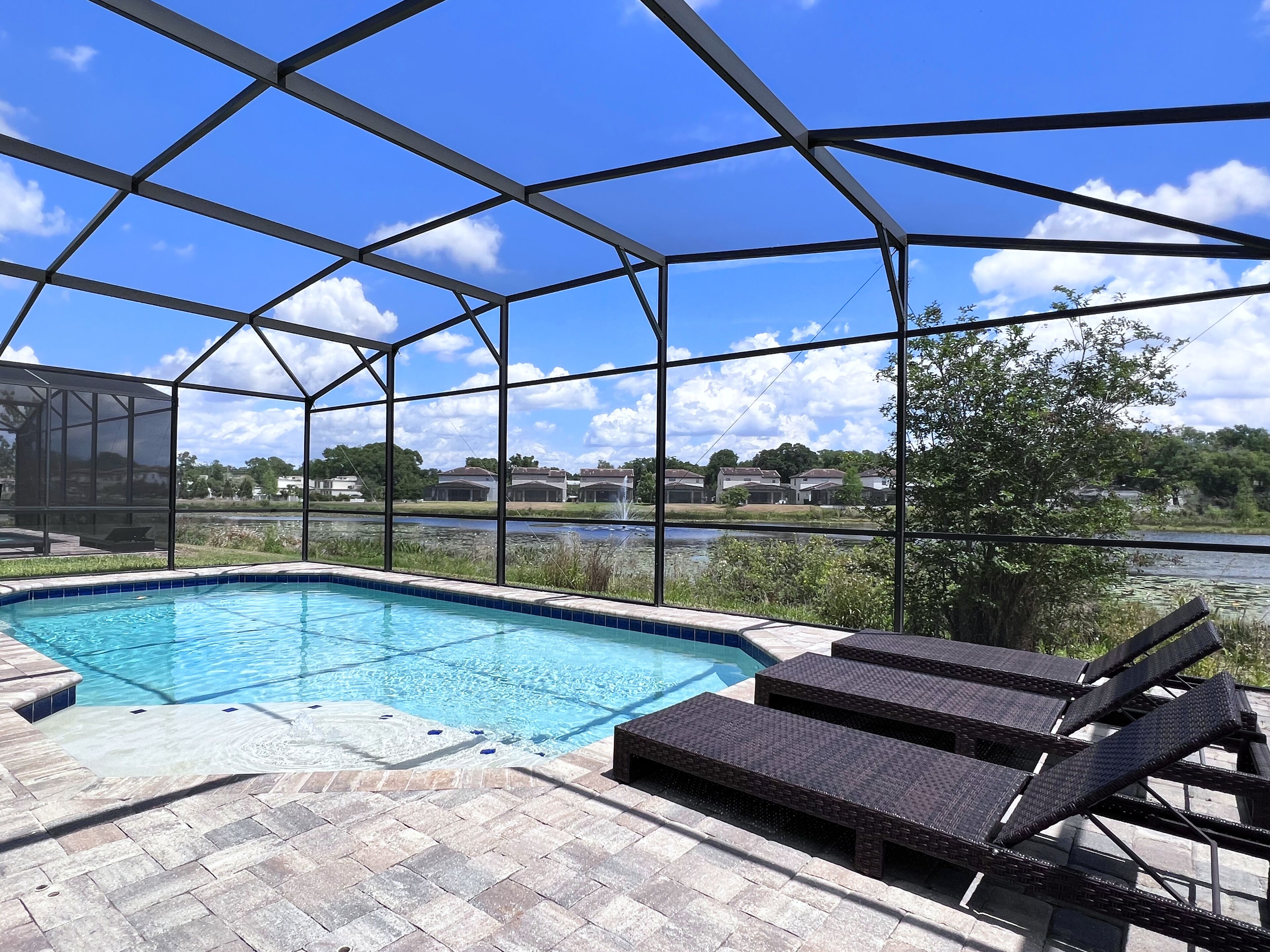 A pool area with a clear view of a lake and houses in the background.