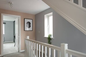Staircase leads to an upper level, with a framed artwork and a potted plant adding to the space.