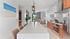 A modern kitchen with a long island, stainless steel appliances, and a pendant light.