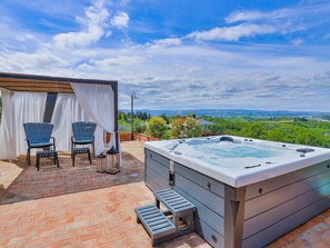 A hot tub with a view of a green landscape, two chairs, and a small table. - Villa in Certaldo ID 4125 (Certaldo)