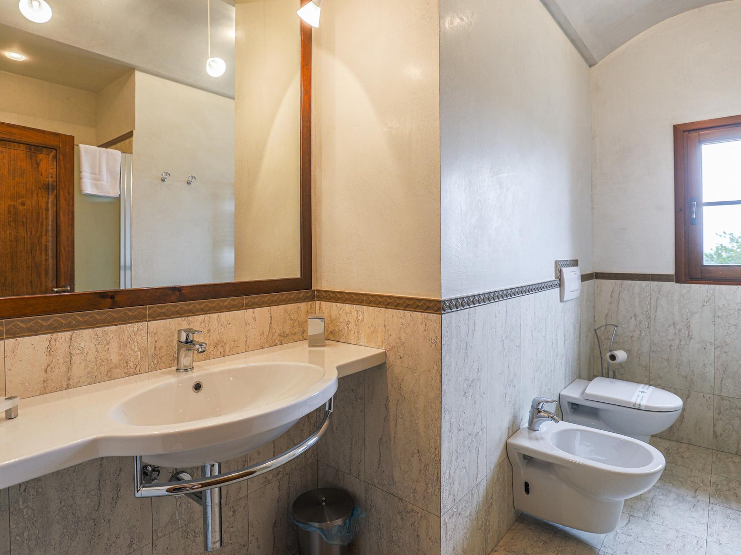 A bathroom with a sink, mirror, and two toilets.
