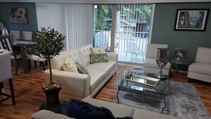 Una sala de estar con un sofá color beige, una mesa de centro de vidrio y una planta en maceta.