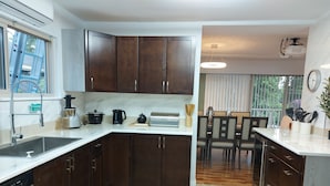 Una cocina moderna con armarios de madera oscura, encimera blanca y un comedor con mesa y sillas.