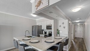 Une cuisine moderne dotée d’un îlot central, de tabourets de bar et d’un réfrigérateur.