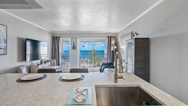 Une cuisine moderne dotée d’un grand îlot central, d’un évier et offrant une vue sur l’océan.