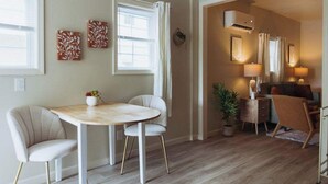A dining area with a round table and two chairs, a sofa, a small side table with a lamp, and a potted plant. - Lamont 1 2bed Pet-Friendly Apt (Johnson City)