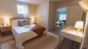 Een slaapkamer met een bed, nachtkastjes, een bureau en een stoel.