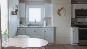 Een moderne keuken met witte kasten, een centraal eiland, een spoelbak en een magnetron.