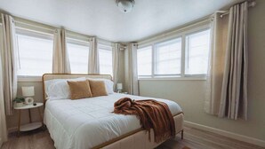 Een slaapkamer met een bed, nachtkastjes en gordijnen.