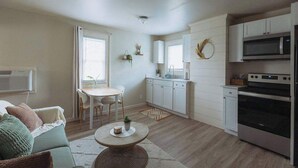 Een compacte leefruimte met een kitchenette, een eethoek en een bank.