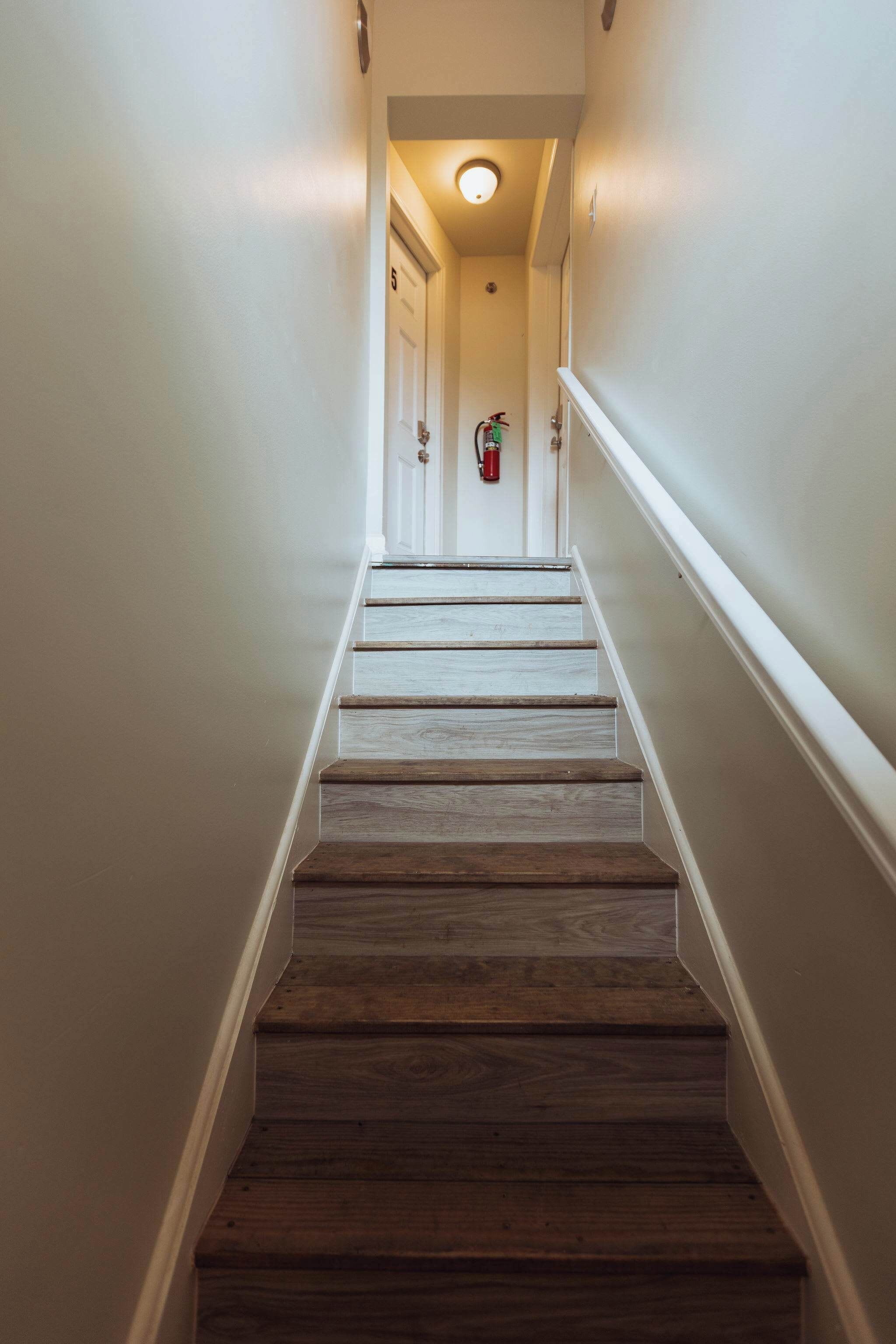 A wooden staircase with white walls and a ceiling light.