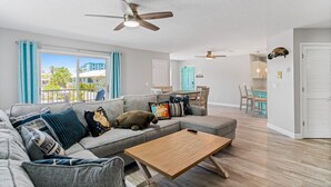 A modern living room with a grey sofa, wooden coffee table, and ceiling fans. - Golf Cart, 2 bed 2 Bath, Heated Pool (Indian Rocks Beach)