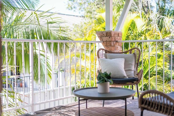 Ein Balkon mit Korbmöbeln, einem kleinen Tisch und einem Blumentopf.