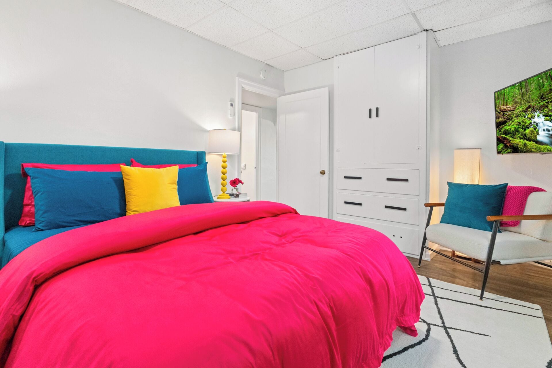 A bedroom with a large bed, a blue sofa, a white wardrobe, and a desk with a chair.