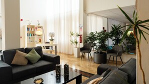 A modern living room with a sofa, armchairs, a coffee table, and a bookshelf.