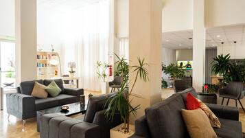 Un hall espacioso con muebles modernos, una estantería y plantas en macetas.