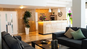 A modern reception area with a marble counter, a sofa, a coffee table, and a potted plant.