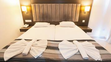 A double bed with a headboard, bedside tables, and two wall-mounted lamps.