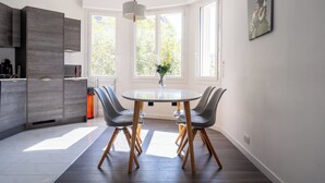 Cozinha moderna com mesa de jantar redonda, duas cadeiras e uma luminária pendente.