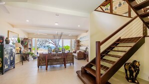 Un espacio habitable amplio con una escalera de madera, una mesa de comedor con sillas y vistas al exterior.